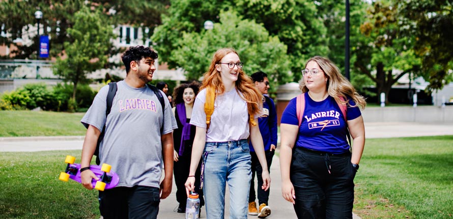 three students walking on Waterloo campus in summer